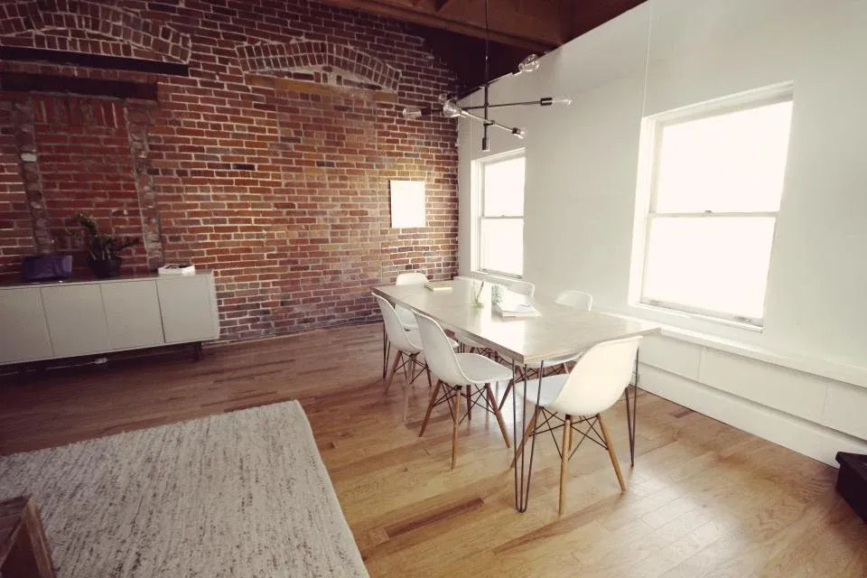 A bright meeting room with a wooden table and white chairs