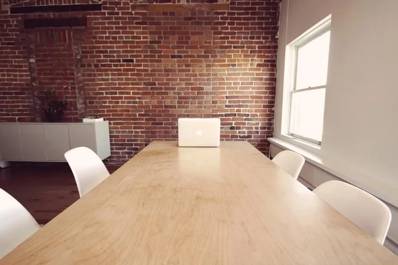 A long wooden table in an office with brick walls